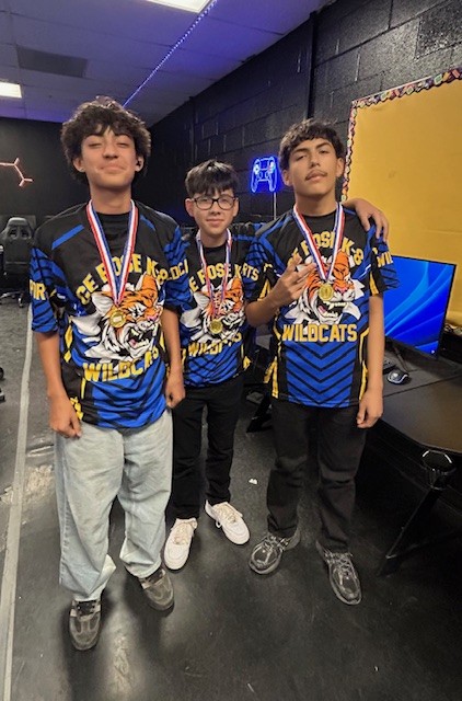 Three boys show off their medals in the esports lab
