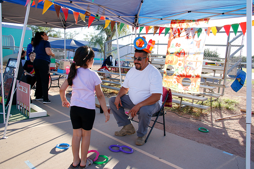 A girl tosses inflatable rings onto a man's hat