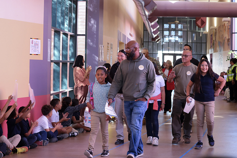 A group of students and veterans parade around the school