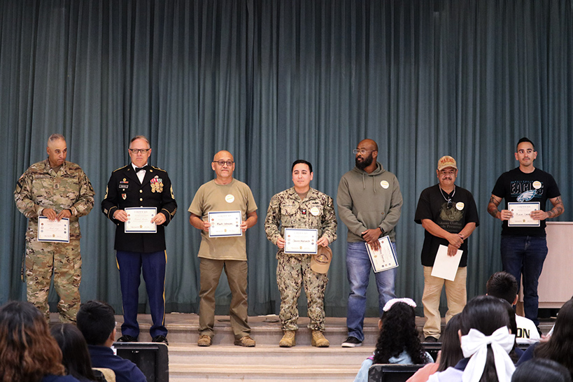 Veterans stand on stage holding their certificates